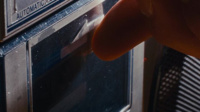 Macro shot of hand loading compact audio cassette into vintage tape player, then closing compartment door