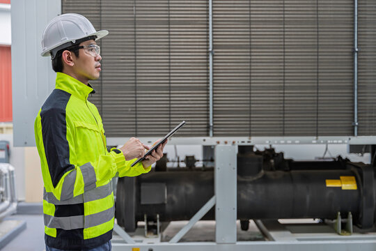 Industrial engineer inspects cooling water pipes at a large industrial facility. Concept of cooling system, engineering, thermal management, utilities, infrastructure, and plant operations.