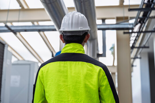 Industrial engineer inspects cooling water pipes at a large industrial facility. Concept of cooling system, engineering, thermal management, utilities, infrastructure, and plant operations.