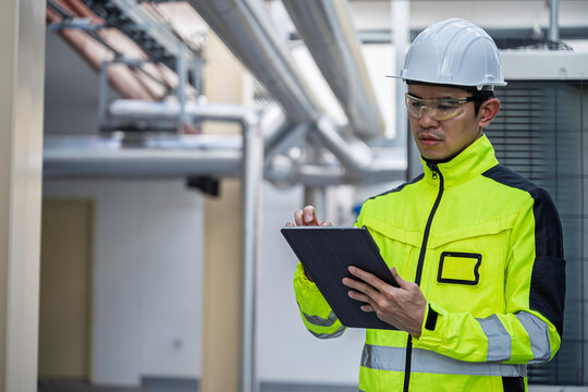 Industrial engineer inspects cooling water pipes at a large industrial facility. Concept of cooling system, engineering, thermal management, utilities, infrastructure, and plant operations.