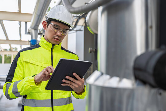 Industrial engineer inspects cooling water pipes at a large industrial facility. Concept of cooling system, engineering, thermal management, utilities, infrastructure, and plant operations.