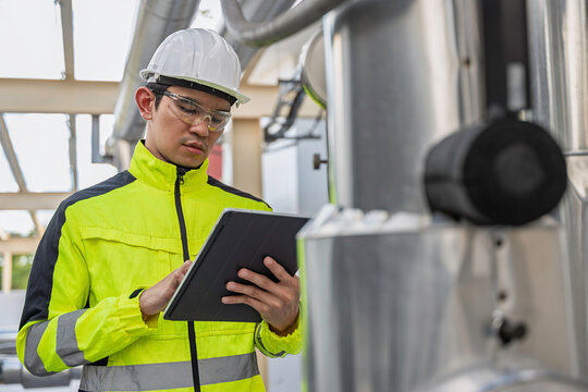 Industrial engineer inspects cooling water pipes at a large industrial facility. Concept of cooling system, engineering, thermal management, utilities, infrastructure, and plant operations.