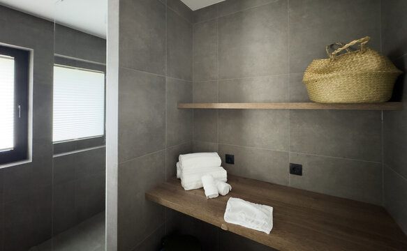 Modern bathroom with ceramic bathroom sink on cabinet with tam and white tile on the wall and mirror. Luxury and stylish interior of room