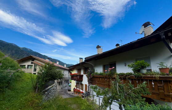  traditional alpine village, featuring rustic wooden buildings and lush green mountain slopes under a bright blue sky