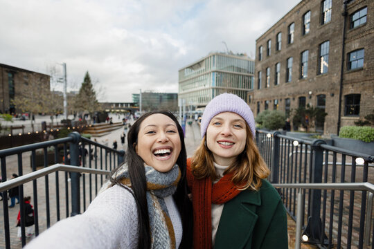 Friends taking selfie showing joy during winter shopping