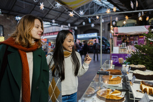 Young women friends shopping at Christmas market bakery