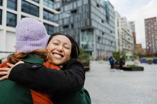 Friends hugging in city during winter meeting