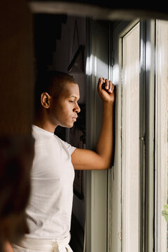 Editorial portrait of man looking out window in dramatic light