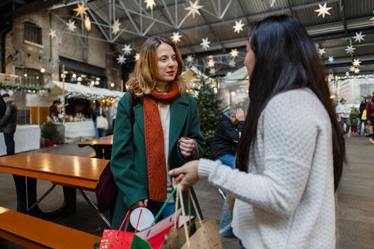 Women friends shopping and talking at christmas market