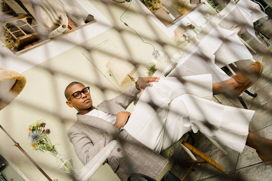 Man in tailored blazer looking at camera through metal grid editorial