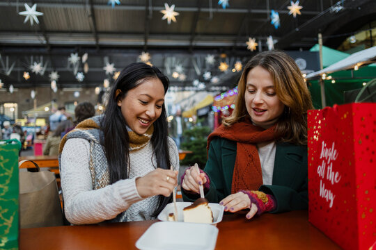 Women friends eating cheesecake at christmas market