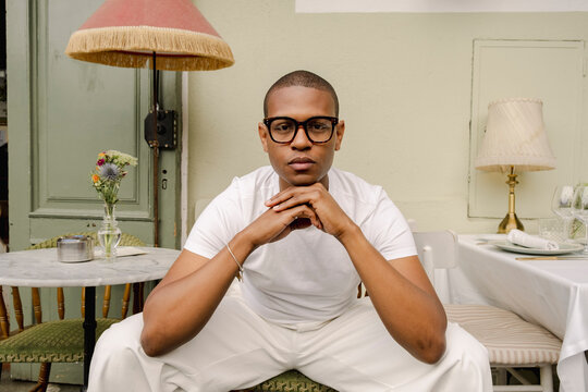 Man in white outfit seated at elegant cafe table editorial fashion