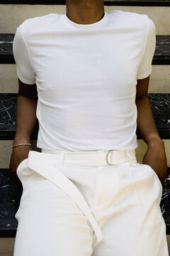 Anonymous man in white outfit seated in fashion detail portrait