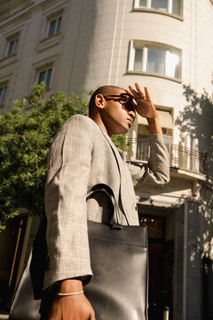 Man shielding eyes with leather briefcase in street editorial