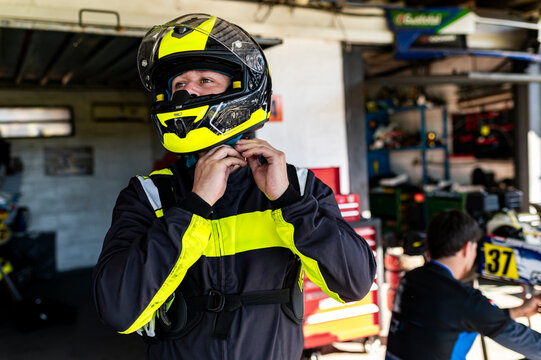 Kart racer fastening helmet strap in pit garage