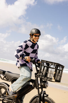 Man laughing while riding e bike on sandy Australian beach
