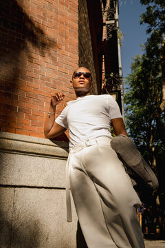 Low angle street style editorial portrait by brick wall