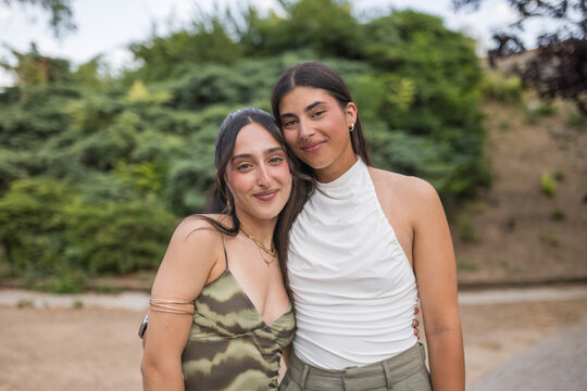 Portrait of a young female couple embracing in a park.