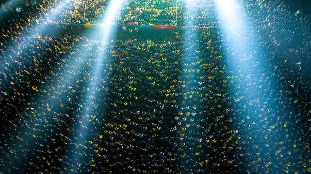 Dhaka, Bangladesh - 28 November 2022: Aerial view of a massive crowd of people gathered at an outdoor event, illuminated by bright stage lights at night.
