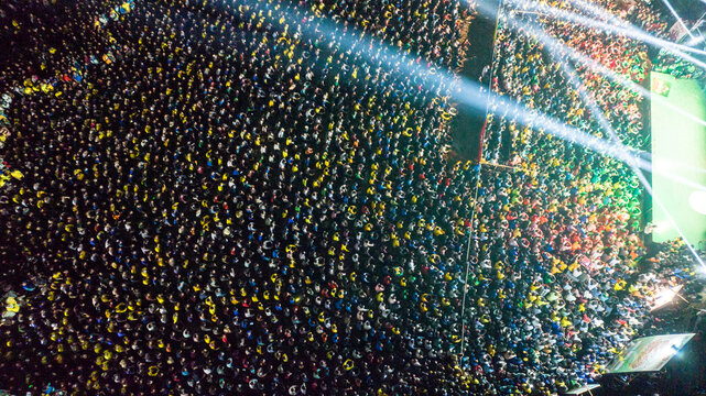 Dhaka, Bangladesh - 28 November 2022: Aerial view of a massive crowd gathered at an illuminated night event with bright stage lights shining over the people.