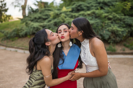Happy Friends Kissing Graduated Young Woman on Cheeks