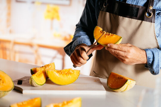 Person cutting fresh melon slices at home kitchen