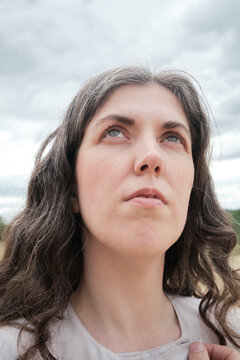 Woman looking upwards in nature on a cloudy day