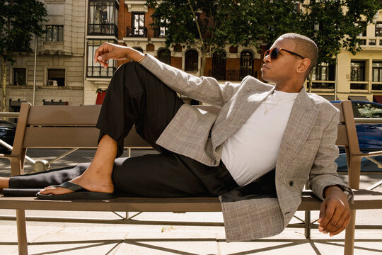 Stylish man reclining on bench in street fashion editorial