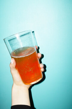 Hand holding drinking stein full of drink on coloured background