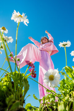 Woman in pink trousers standing among wildflowers
