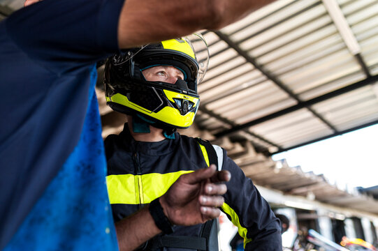 Helmeted kart racer talking with teammate in pit