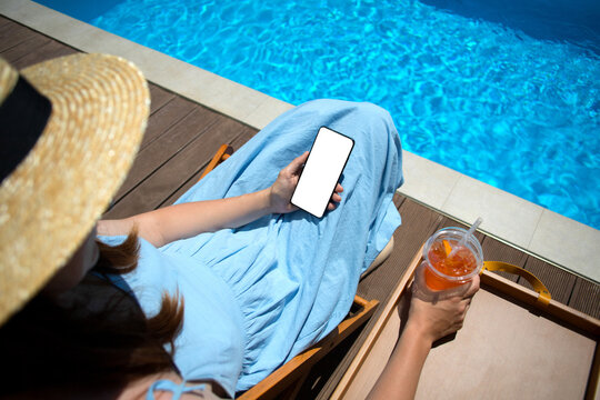 Anonymous middle-age woman with mobile phone near swimming pool.
