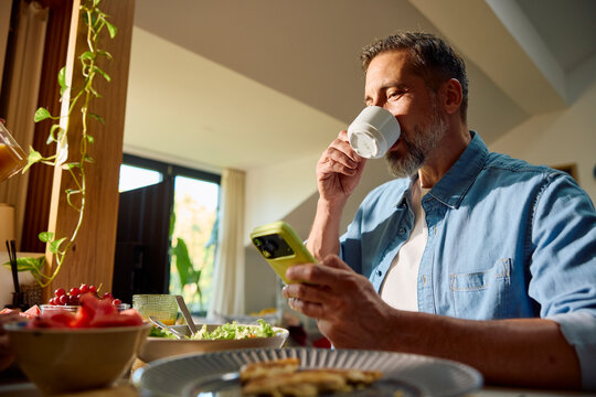 Smiling man grabs a cup of coffee after finished meal