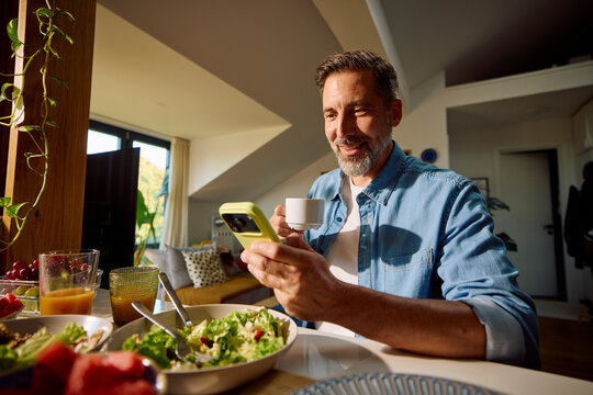 Smiling man grabs a cup of coffee after finished meal
