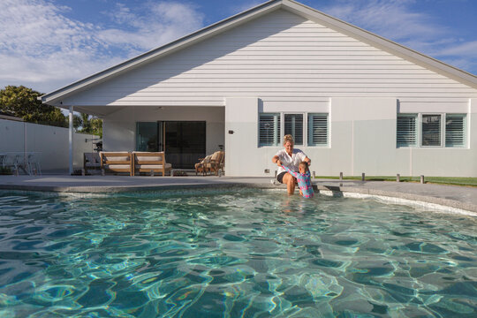 Mum and young son playing in the backyard pool