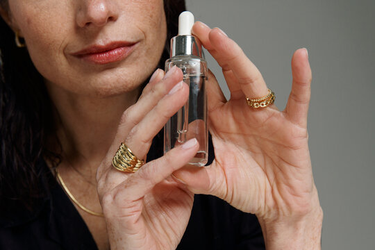 Woman Holds a Dropper Bottle With Care in a Light Setting