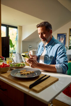 Smiling man grabs a cup of coffee after finished meal