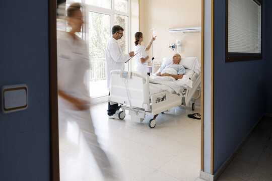 Medical professionals caring for elderly patient in hospital room