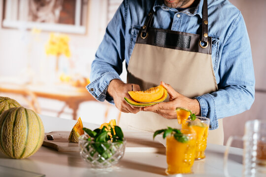 Man preparing fresh melon fruit for healthy juice