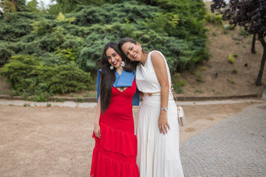 A proud mother embraces her newly graduated daughter outdoors.