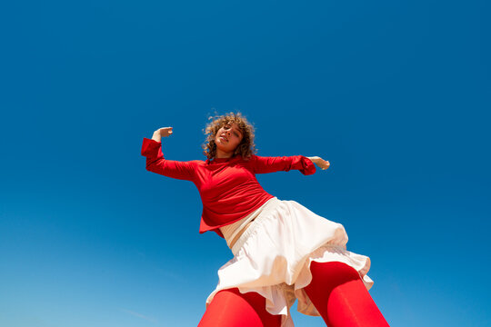 Woman posing dynamically against clear blue sky