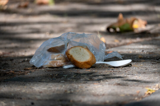 Discarded Bread and Plastic Waste on Pavement