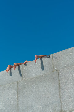 Bare feet hanging over concrete wall