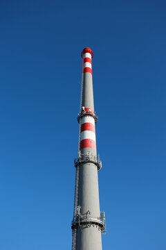 Smokestack and chimney against a clear blue sky. Industrial architecture and building with no smoke, symbolizing zero emissions, reduced pollution, and clean air. Copy space.