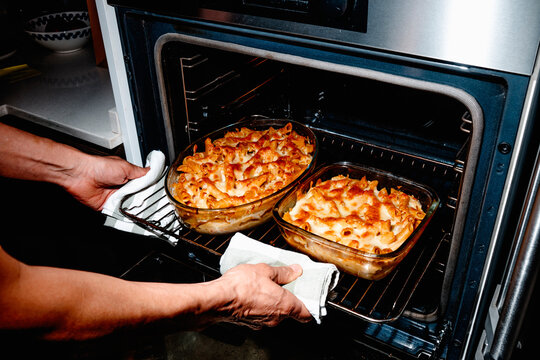 a man removing baked macaroni and cheese from the oven