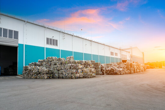 Pressed pet plastic bottles into briquettes, stored in an outdoor storage facility at a waste recycling and sorting plant workshop.
