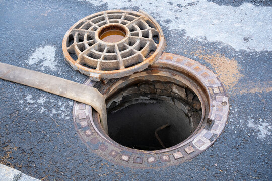 Open Manhole on Asphalt Road with Removed Cover