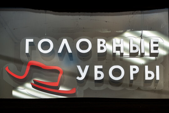 Illuminated modern retail store signboard with text in Russian meaning Headwear