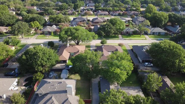 Shaded backyard fences surround single story brick dwellings across suburb Dallas. Verdant deciduous trees shade quiet residential lots near Spring Trail Park, Coppell, Texas