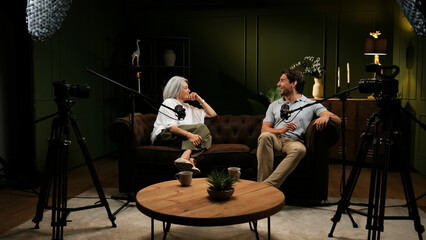 Obraz na płótnie Canvas Two people engaging in a lively discussion with microphones and cameras during a live broadcast